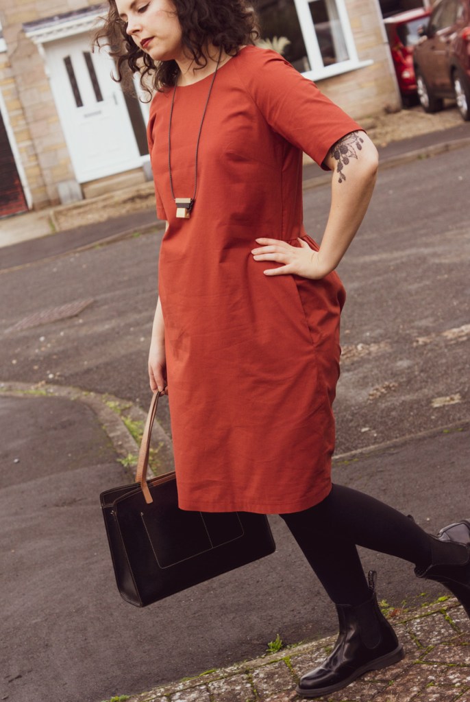 Full body photo of Vicky wearing The Gathered Dress in a rust coloured fabric. 
